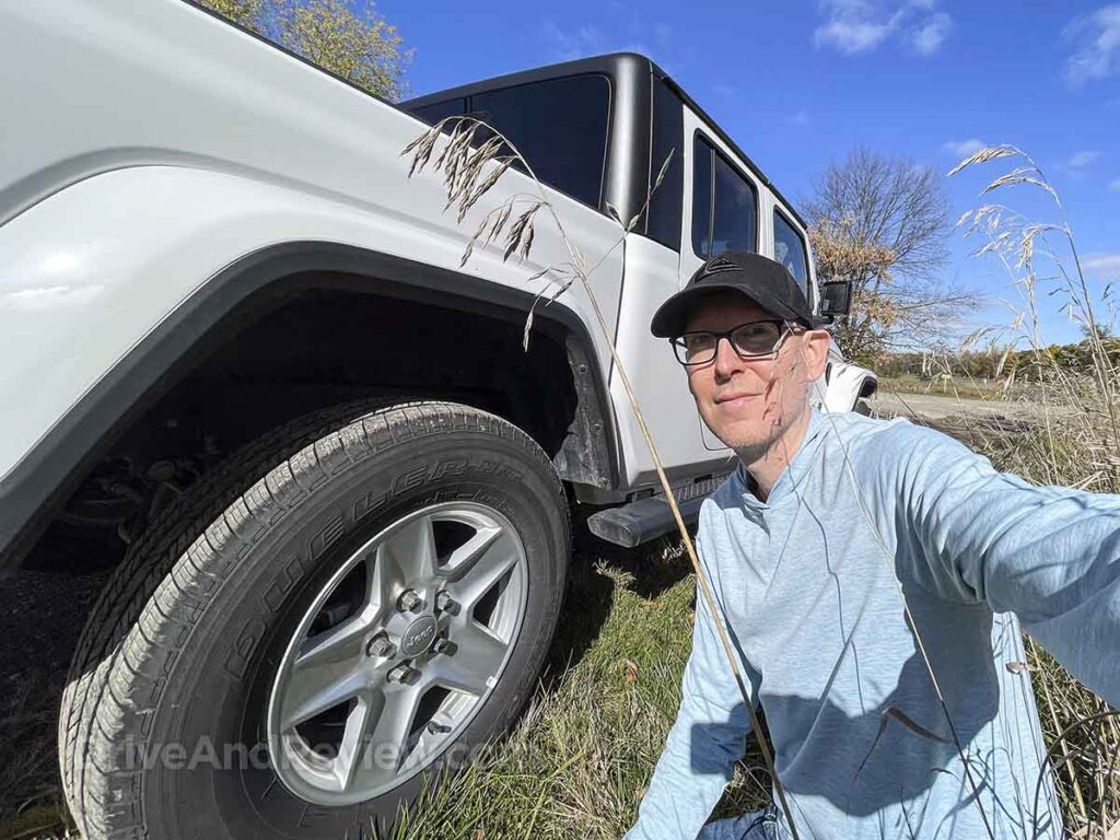 Scott posing next to a white Jeep gladiator