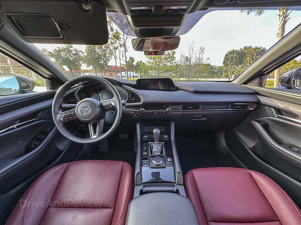 2026 Mazda 3 red interior with black accents (looking forward showing the dashboard and steering wheel)