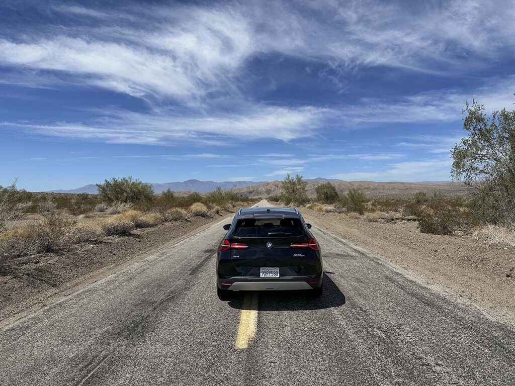 Rear end of a black 2026 BMW X3 on an empty road in the California desert