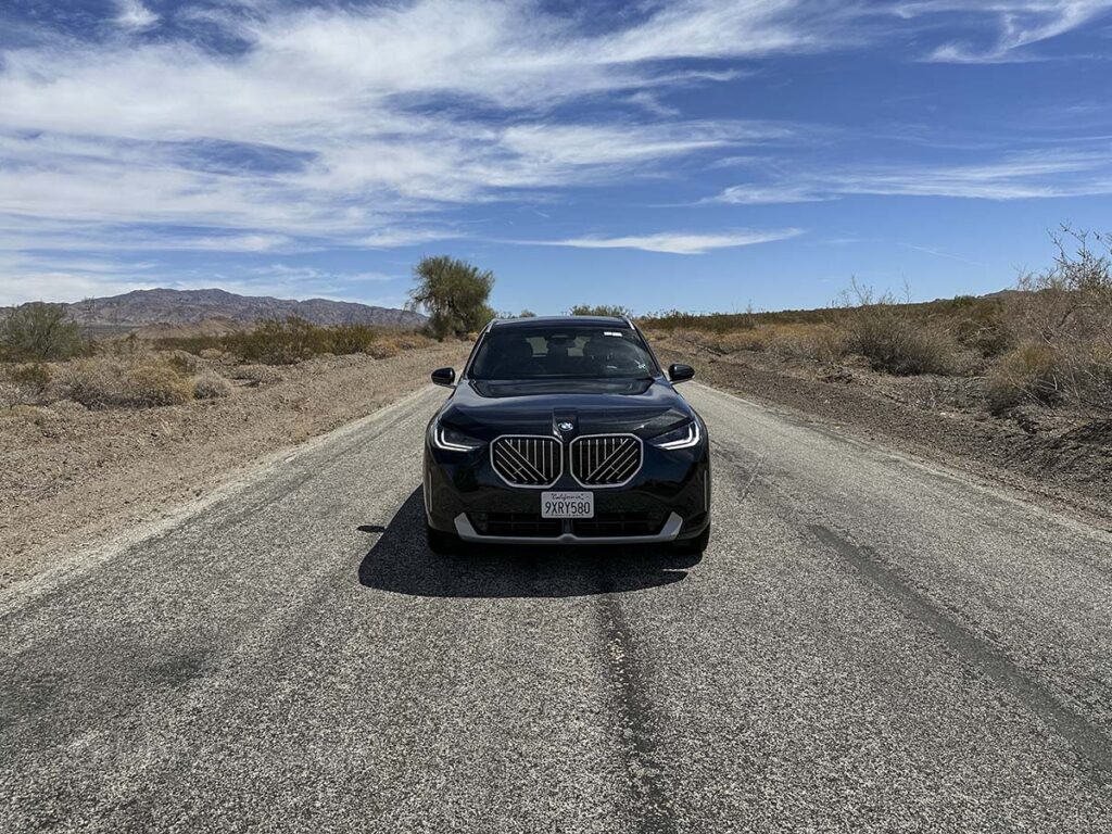 Front end of a black 2026 BMW X3 on an empty road in the California desert