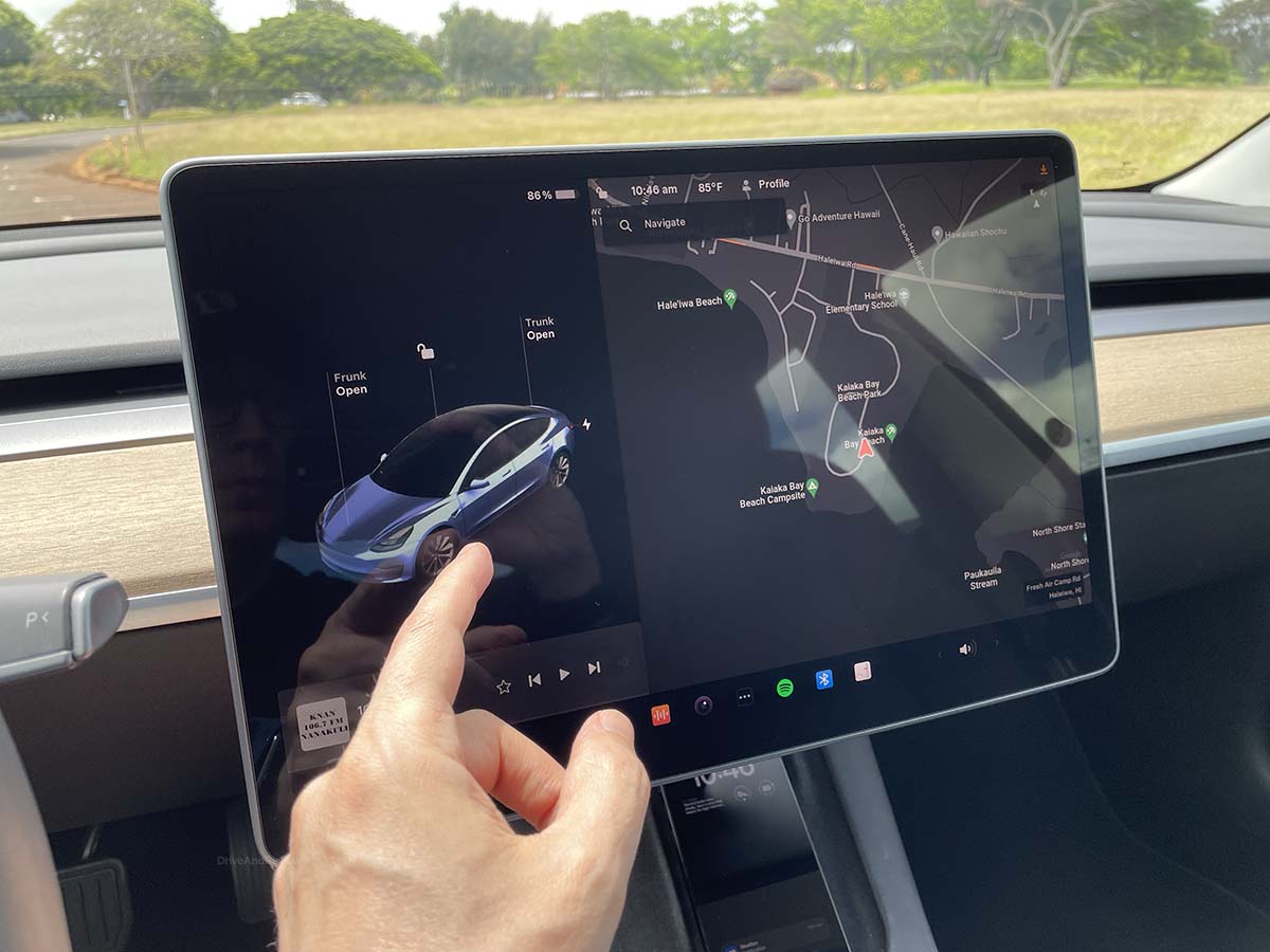 Large display screen in the interior of the 2023 Tesla model 3 showing trunk opening menu on the left, and a navigation map on the right