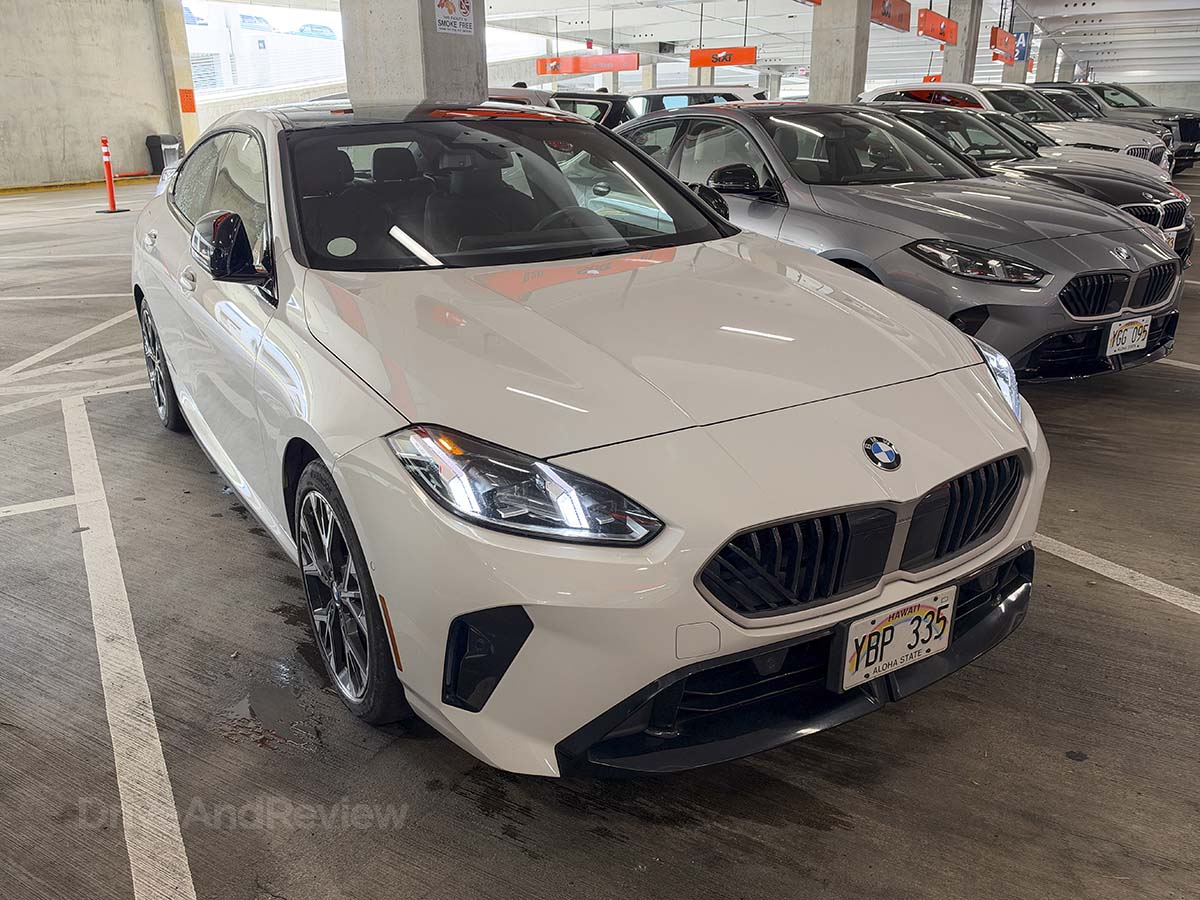 Front 3/4 view of a white 2026 BMW 228 xDrive parked at the Sixt rental car garage Honolulu airport