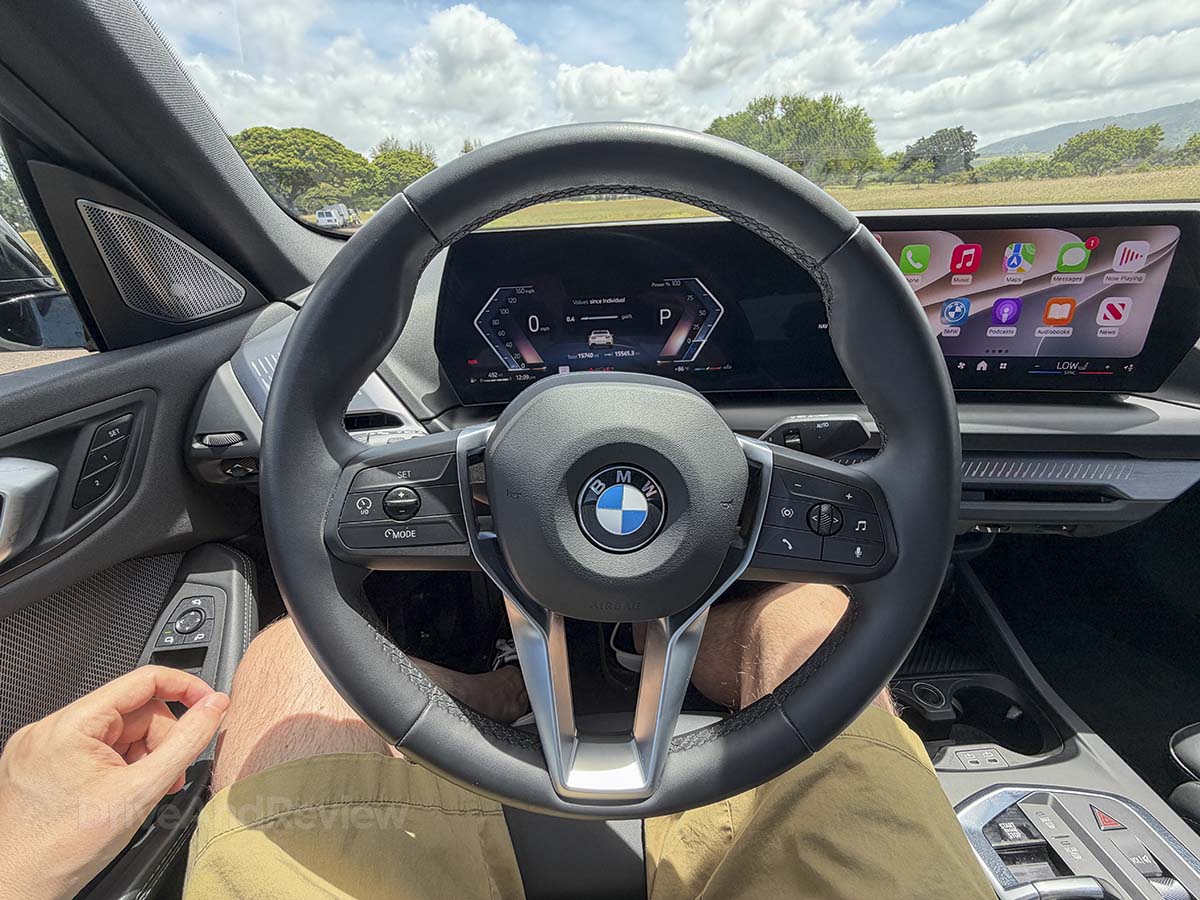 Sitting behind the wheel of a 2026 BMW 228 xDrive with the gauge cluster and infotainment screen on